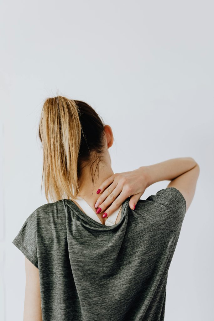 pexels photo 4506108 4506108 Back view of blond faceless lady in casual t shirt and manicure demonstrating pain spot on back while sitting near white wall