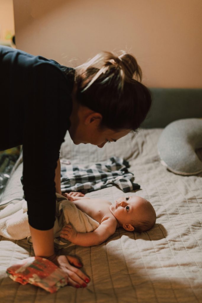 pexels photo 6849431 6849431 Mother lovingly interacts with her newborn baby on a cozy bed indoors.