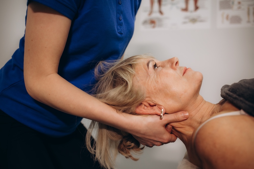 a rehabilitator massages the neck of an elderly woman a rehabilitator massages the neck of an elderly woman
